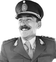 a man in a military uniform is smiling and wearing a hat and tie .