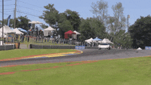 a white car is driving down a race track with a sign that says ' racing ' on it