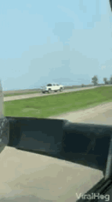 a white truck is driving down a highway next to a grassy field and a sign that says viralhog