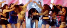 a group of women are dancing on a stage with a man standing in the middle .