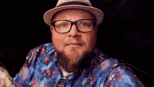 a man with a beard and glasses is wearing a blue shirt