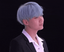 a young man with blue hair is wearing a black suit and white shirt