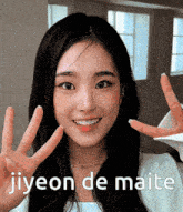 a woman is smiling and making a peace sign with her hands and the words jiyeon de maite below her .