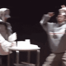 a group of people are dancing on a stage in front of a table with cups on it .