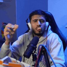 a man wearing headphones and a microphone is eating a sandwich