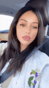 a woman is sitting in a car with a seat belt around her neck .