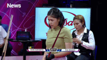 a woman holding a pool cue in front of a tv screen that says i news