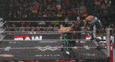 two wrestlers are wrestling in a ring with a referee in the background