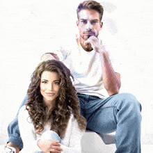 a man and a woman are sitting next to each other on a white box