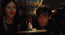 a boy and a girl are looking at a candle in a dark room