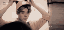 a young man is wearing a cat ear hat and looking at himself in the mirror .