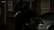 a bbc advertisement shows a car parked in front of a brick house
