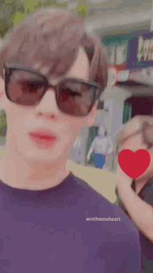 a man wearing sunglasses and a purple shirt with wintheoneheart on it