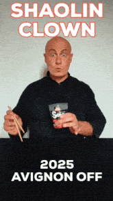 a man holding chopsticks in front of a poster that says shaolin clown 2025 avignon off