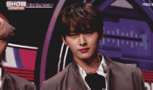a young man stands in front of a show champion logo