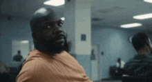 a man with a beard is sitting in a chair in a room looking at the camera .