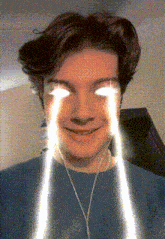 a young man with glowing eyes is smiling and wearing headphones
