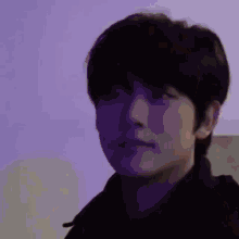 a close up of a man 's face with purple lights behind him .