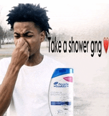 a man is holding his nose in front of a bottle of head and shoulders shampoo .