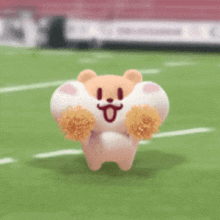 a stuffed animal is running on a football field with pom poms .