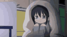a little girl is wrapped in a blanket and sitting in front of a tv .