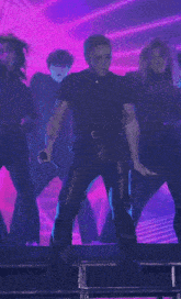 a man in a black shirt is holding a microphone while dancing on a stage