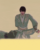 a man in a green robe is standing next to a man laying on the ground