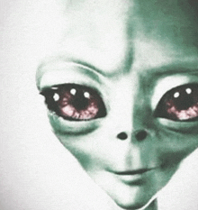 a close up of a grey alien 's face with red eyes