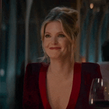 a woman is sitting at a table with a glass of wine and laughing .