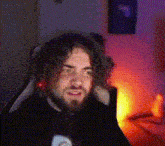 a man with a beard and long hair is sitting in a chair in front of a computer screen .