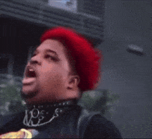 a man with red hair and a beard is making a funny face with his mouth open .