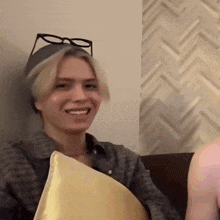 a man wearing glasses is smiling while holding a pillow