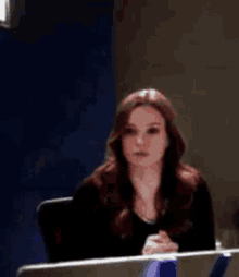 a woman is sitting in a chair with her hands folded in front of her .