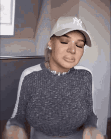 a woman wearing a ny hat and a sweater is making a funny face