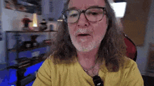 a man with long hair and glasses is sitting in front of a computer .