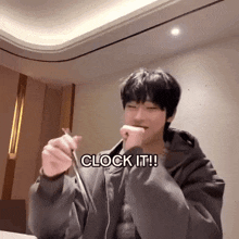 a young man is holding something in his hand with the words " clock it " above him