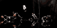 a group of people are dancing in a dark room with their reflections in the water .