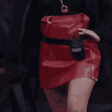 a woman wearing a black turtleneck and a red skirt is waving her hand .