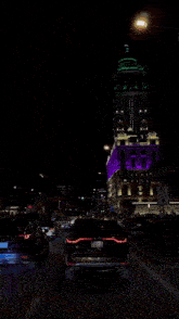 a purple building is lit up at night with a parking sign in front of it