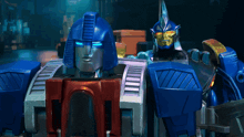 two transformers are standing next to each other and one has the letter t on his chest