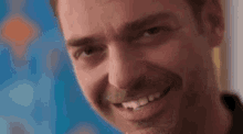 a close up of a man 's face with a beard smiling .