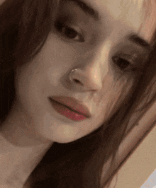 a close up of a woman 's face with a nose ring and red lipstick .
