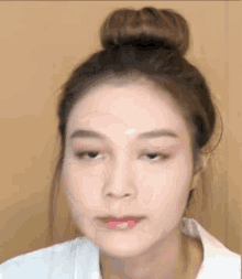 a close up of a woman 's face with her hair in a bun .
