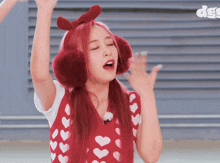 a woman with red hair wearing ear warmers and a red vest with hearts on it