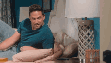 a man in a blue shirt is sitting on a bed