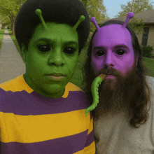 a man with a green face and a purple face has a green tentacle sticking out of his mouth