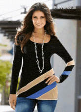a woman wearing a long necklace and a black shirt with blue and tan stripes on the sleeves