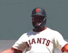 a baseball player wearing a giants jersey and a black helmet