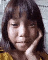 a young girl with a hand on her face looks at the camera