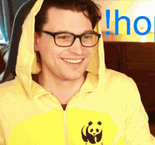 a man wearing glasses and a yellow hoodie with a panda logo on it